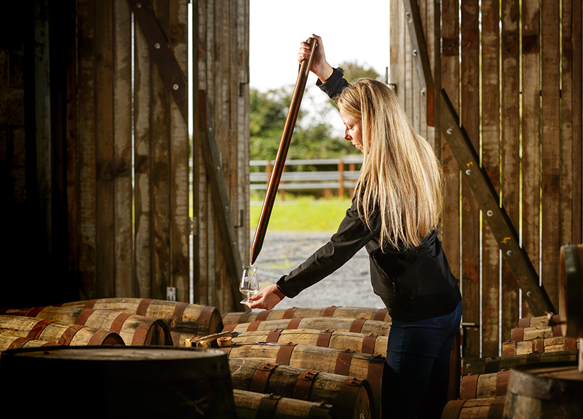 Louise McGuane taking a sample from a cask.