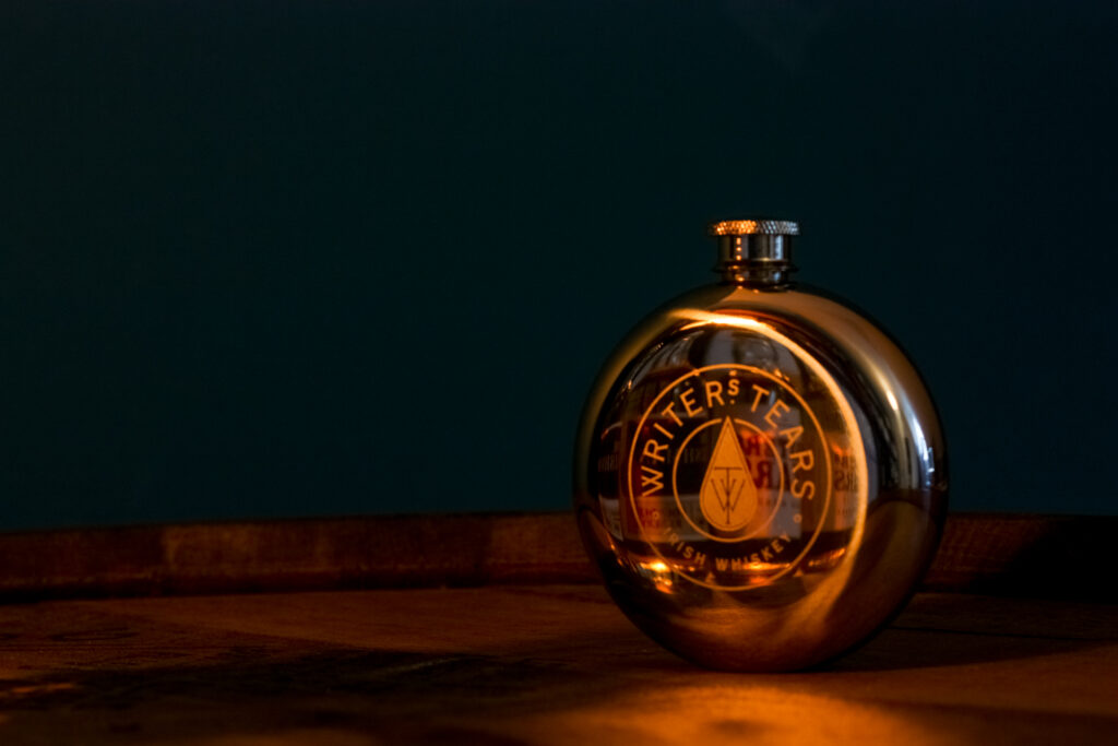 Writers' Tears flask with the samples from the Walsh Whiskey Tweet Tasting 2021 reflected on it.